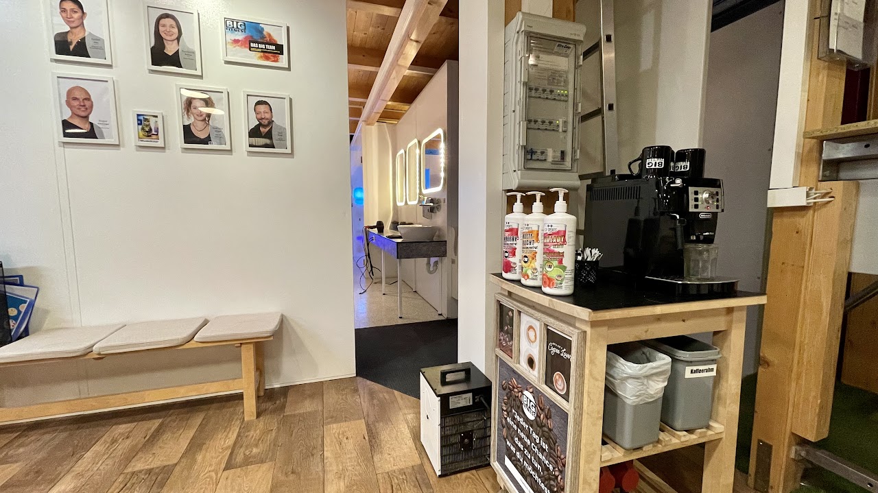 Empfangsbereich von BIG Fitness Laufen mit Teamfotos und Kaffeestation